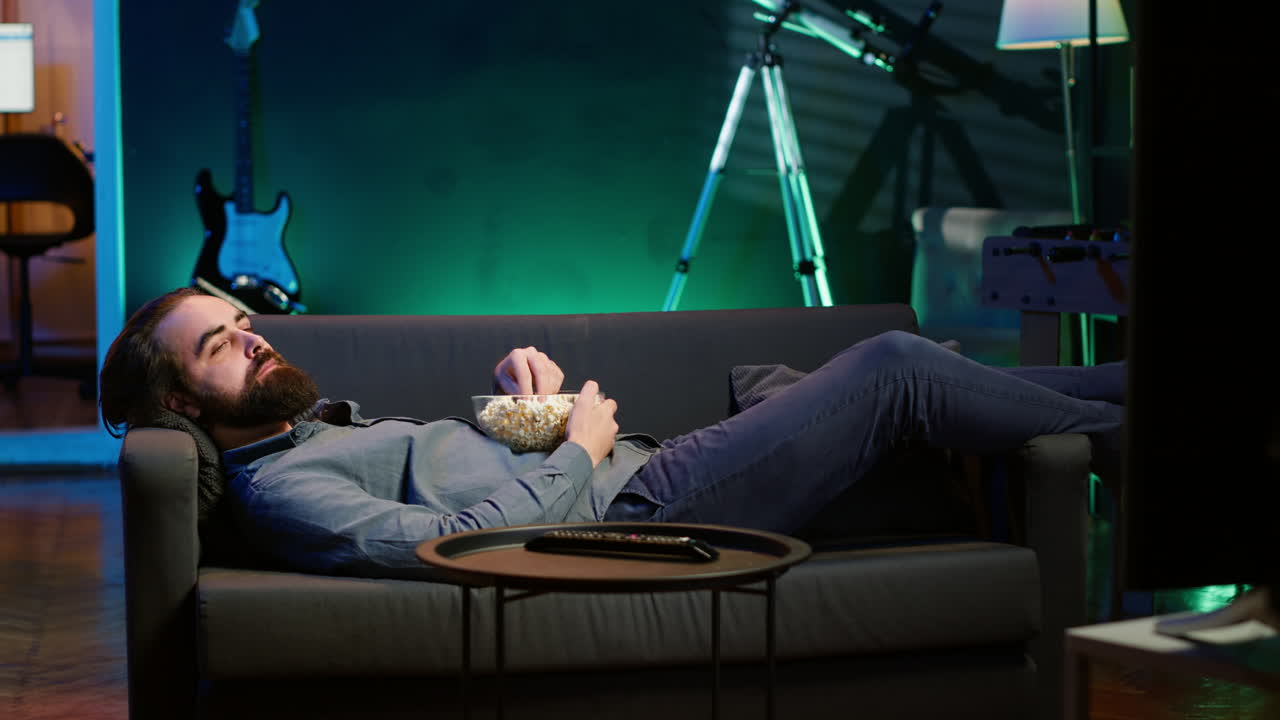 소파에 누워서 tv에서 좋은 영화를 보고 있는 낙관적인 집주인