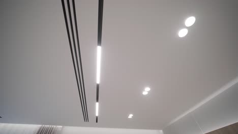 the image shows a close-up view of a modern hallway ceiling with sleek, built-in led strip lighting and minimalist, dark-colored doors, evoking a contemporary and stylish interior design.