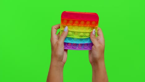 hands playing popular squishy silicone bubbles sensory toy game isolated on chroma key background