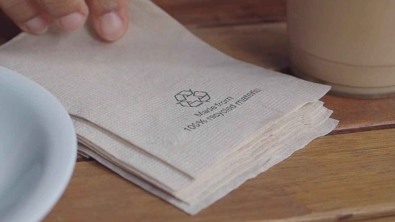 Hand Taking a Recycled Paper Napkin from a Stack