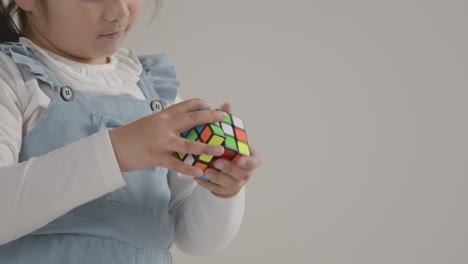 retrato de estudio de una joven en el espectro asd resolviendo un cubo de rompecabezas contra un fondo blanco