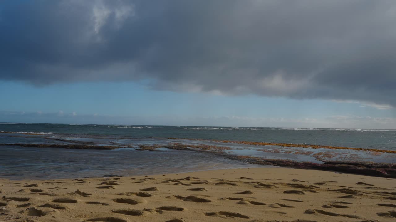 큰 폭풍우 구름 선반이 머리 위를 지나갈 때 해변에 굴러가는 파도의 시간 경과