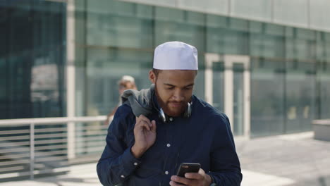 Un-Joven-Hombre-De-Negocios-Del-Medio-Oriente-Con-Auriculares-Se-Pone-El-Abrigo-En-El-Hombro-Y-Confía-En-Un-Smartphone-Profesional