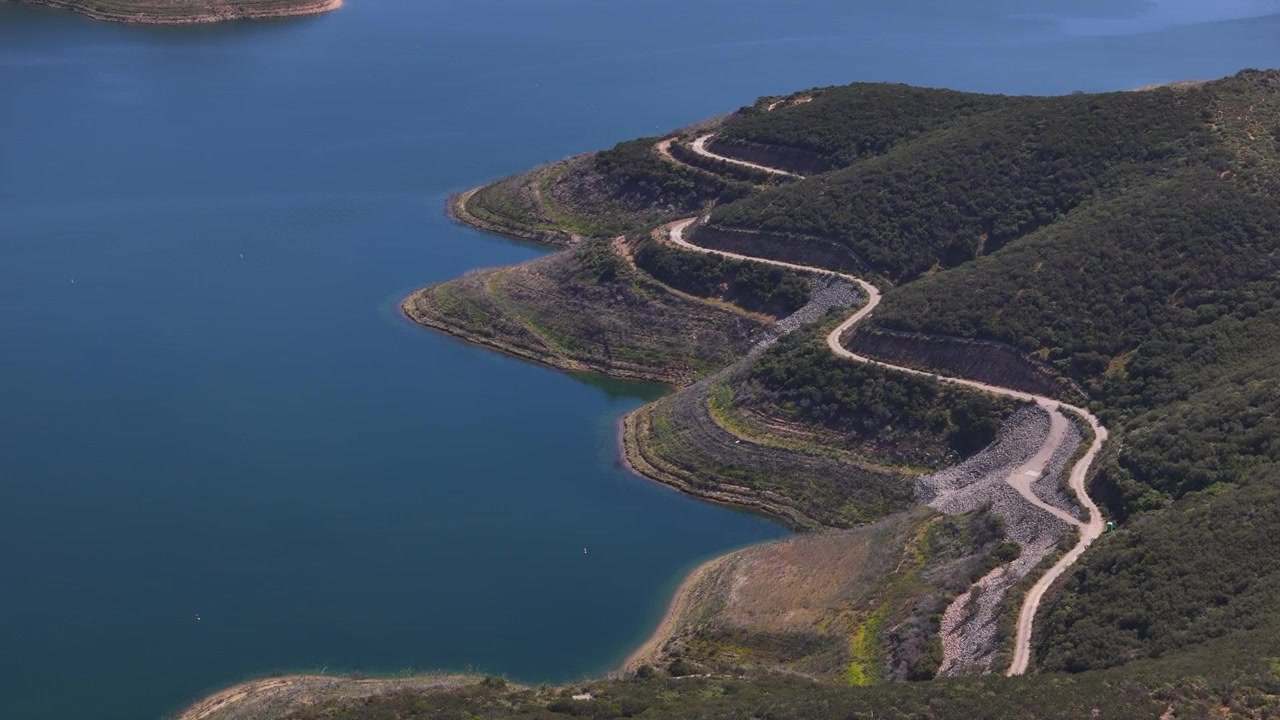 Záběr dronem na silnici na členitém pobřeží, jezero San Vicente Water Reservoir v Kalifornii, USA.