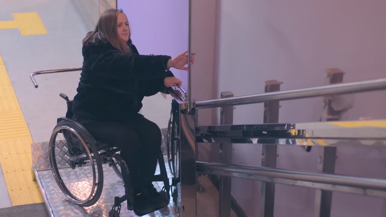 una mujer con discapacidad en silla de ruedas sube las escaleras en un ascensor mecánico.