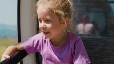 un niño curioso con una camiseta de lila se sienta en una góndola de cable