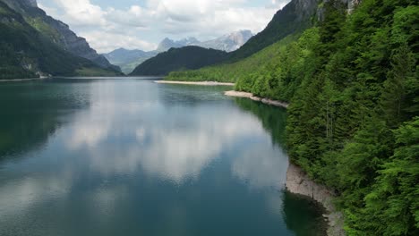 Reflejo-De-Agua-Clara-En-El-Lago-Klöntalersee-Glarus-Kanton-En-Suiza-Con-Impresionantes-Vistas-A-La-Montaña-Como-Telón-De-Fondo-Y-Drones