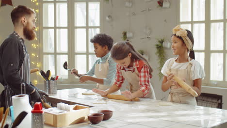 children and chef rolling dough during cooking class