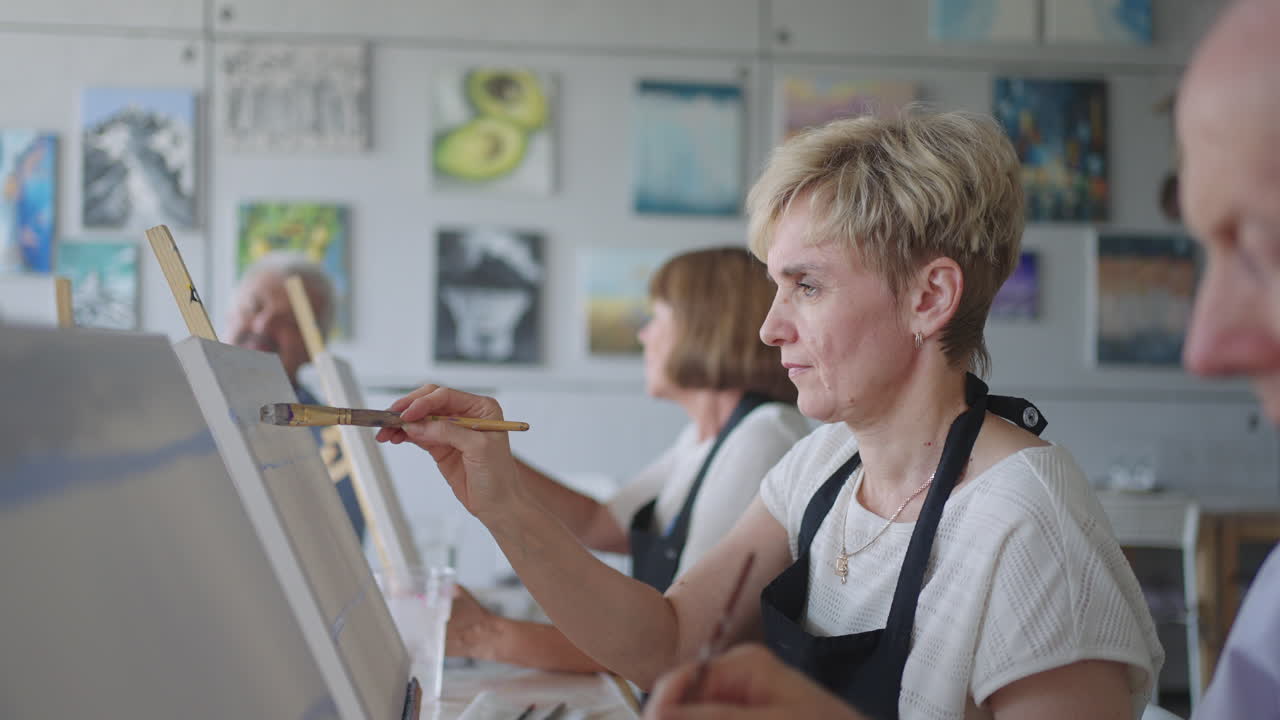 пожилые люди посещают курсы рисования. учитель помогает пенсионерам, которые посещают курсы рисования, рисовать. группа друзей-пенсионеров на уроке рисования