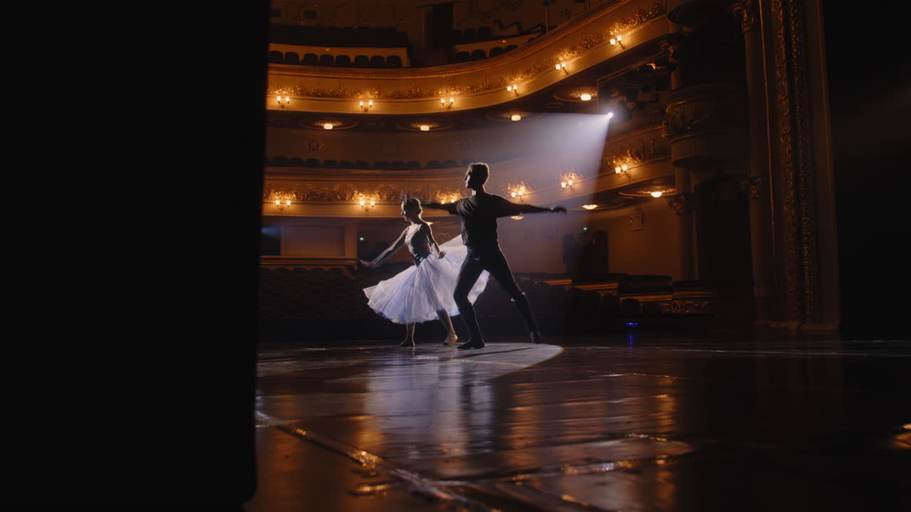pair of Ballet Dancers Practice on Theater Stage Beautiful Pair of Ballet Dancers Practice Visual Moves on Theater Stage Graceful Ballerina together with Partner on Performance Rehearsal Spotlights Light up the Stage Classical Ballet Art Concept