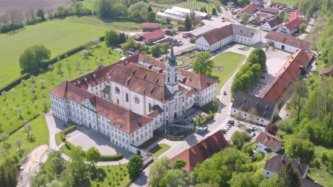 Impressive view at the bavarian monastery Schäftlarn from above while cars are passing the access road to the beautiful bavarian place, germany.