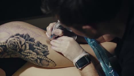 artista del tatuaje trabajando en un tatuaje de pierna