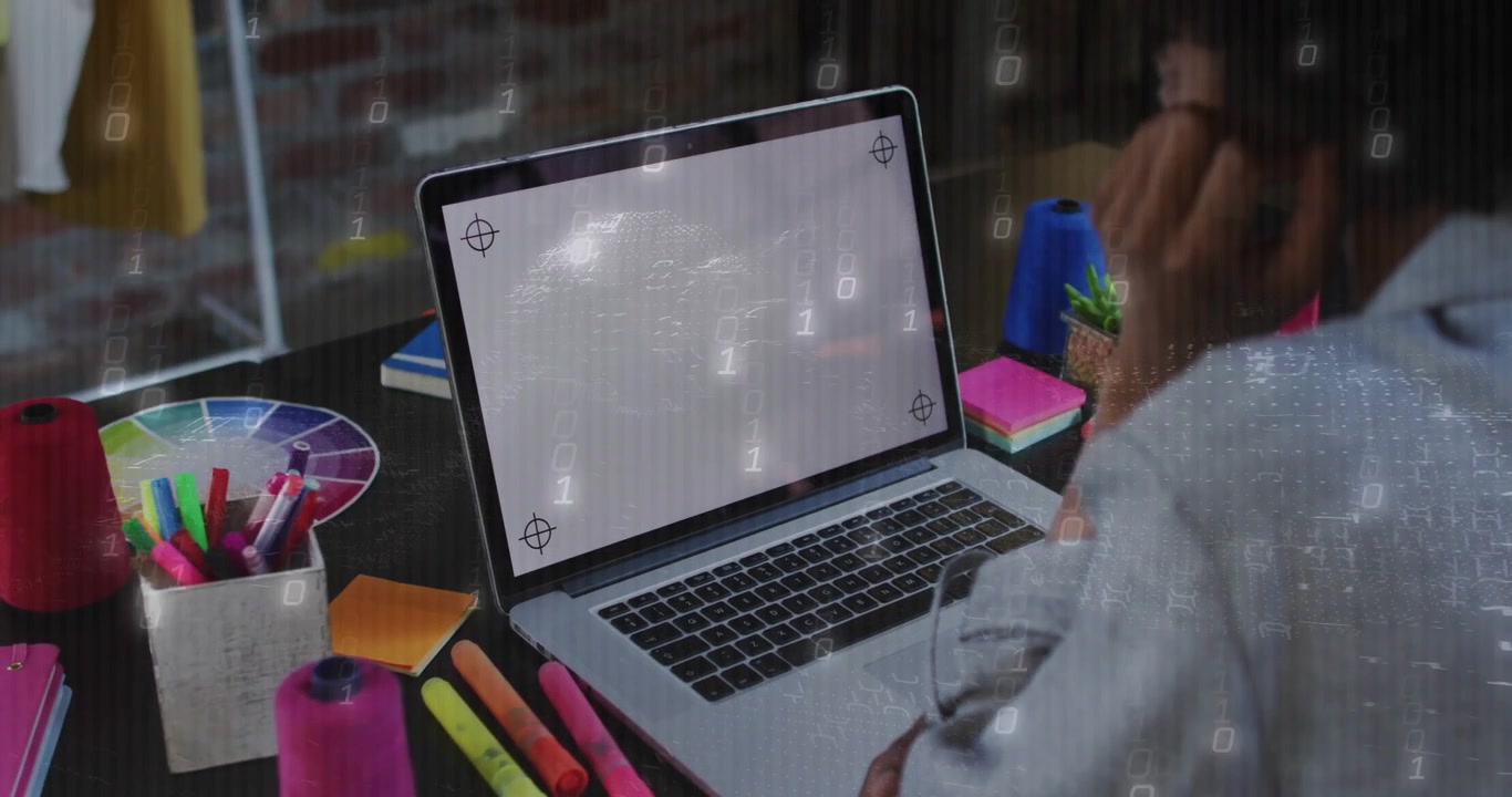 Mulher em mesa de design desordenada testando laptop, alcançando o trackpad e ativando sobreposição binária
