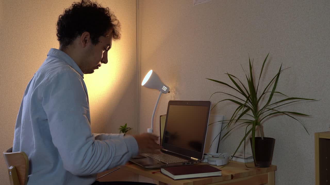 un hombre con síntomas de coronavirus estornuda mientras trabaja en su computadora portátil en la oficina del hogar - toma de primer plano