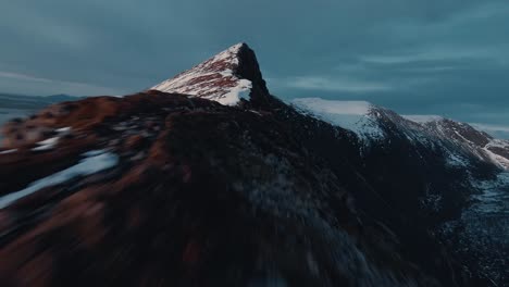 fpv flying along snow covered ridge towards mountain peek, norway