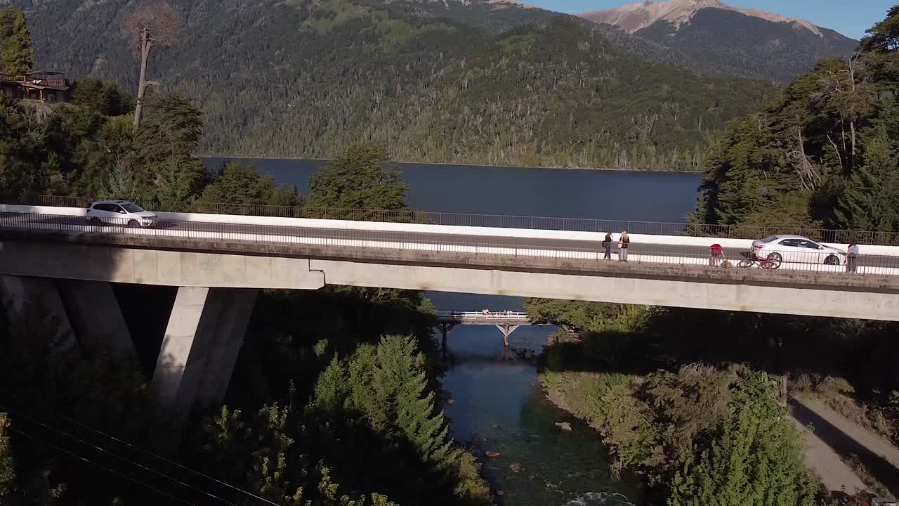 puente sobre el rio correntoso con el lago nahuel huapi y las montañas al fondo
