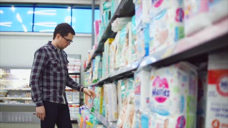 man shopping for baby diapers in a supermarket