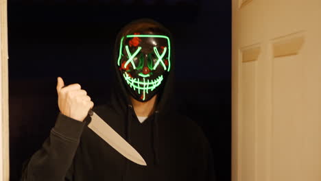 a scary slasher killer in a generic anonymous halloween horror mask pulling a knife on his murder victim