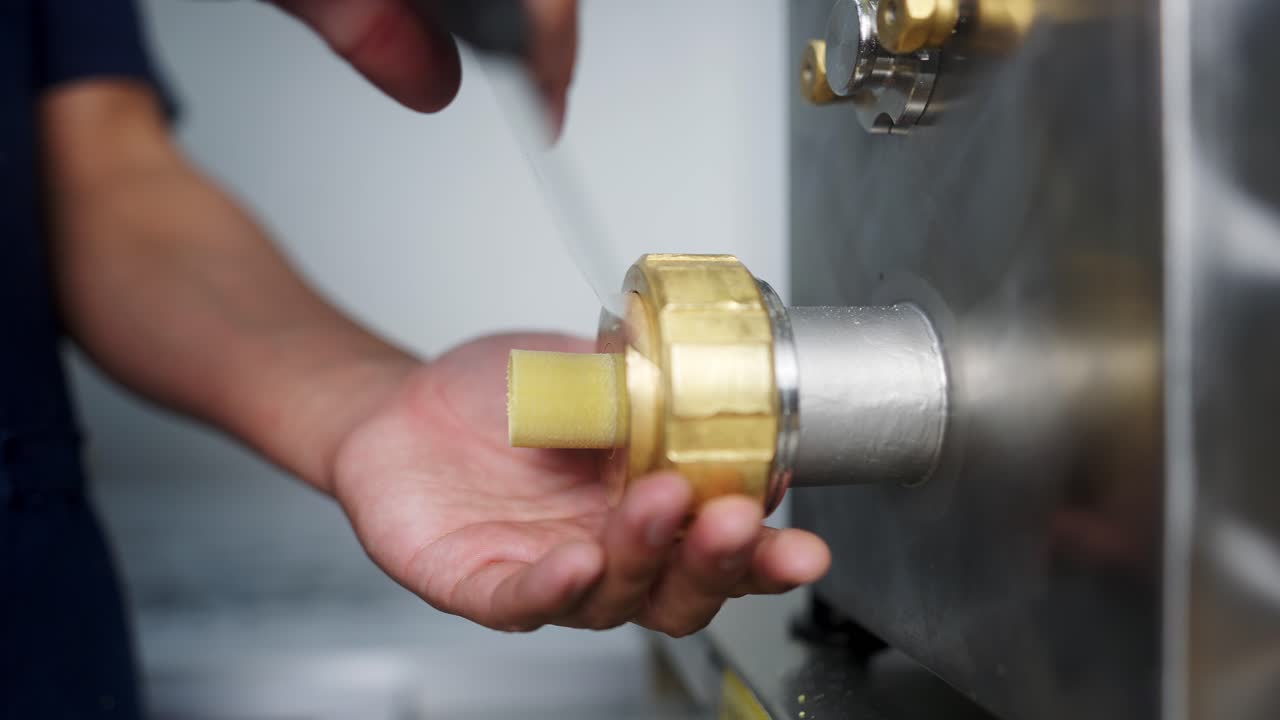 Close up slow motion view of a Chef slicing rigatoni pieces coming out of a pasta machine.