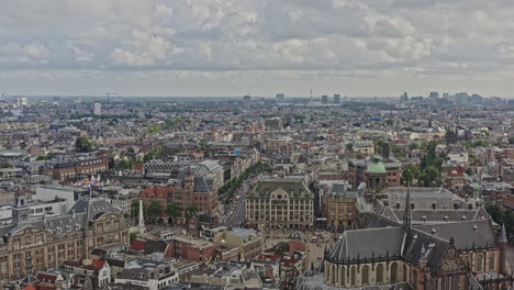 amsterdam netherlands aerial v9 reverse flying away from popular cultural landmark dam square, capturing downtown cityscape at binnenstad neighborhood with heritage dutch architectures - august 2021