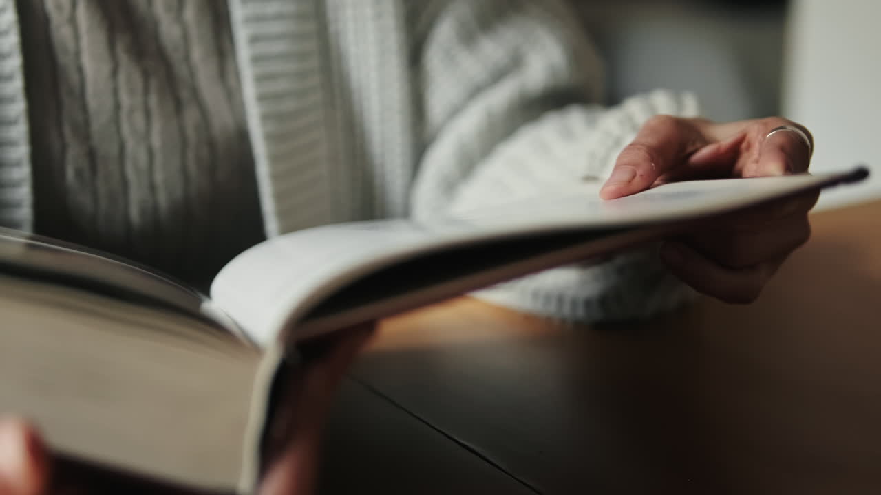 Nahaufnahme einer Person, die ein Buch liest und Seiten umblättert.