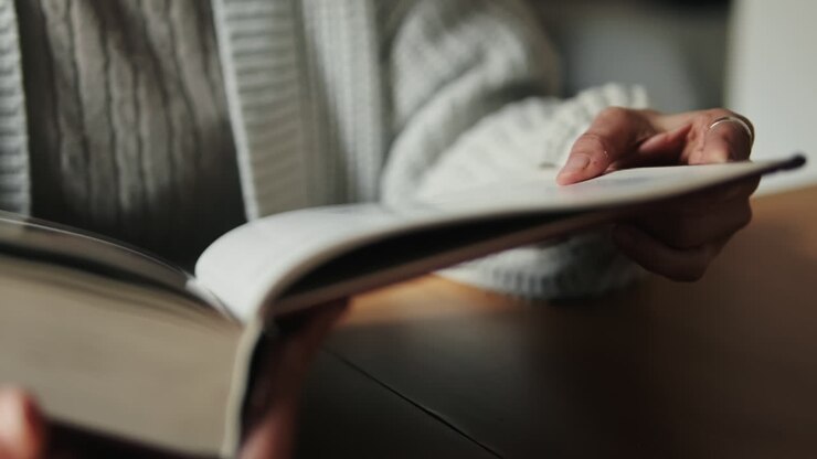 Primo piano di una persona che legge un libro e gira le pagine.