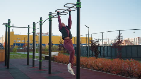 fitness enthusiast hangs from pull up bars in urban park, pumping body through dynamic movement under bright sky, showcasing strength, balance, and determination during outdoor calisthenics session