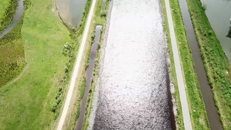 Blick-Von-Oben-Auf-Den-Kanal-Und-Den-Weg-Mit-Sonnenlicht,-Das-Das-Wasser-Erstrahlen-Lässt