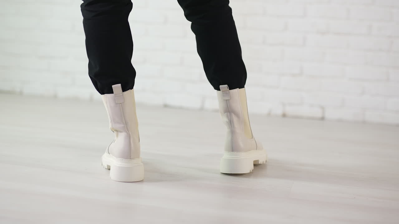 Woman wearing cream colored platform ankle boots with black pants