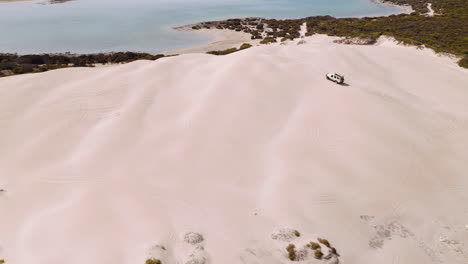 aerial over a 4wd safari jeep vehicle driving across the sand dunes of south australia