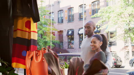 una pareja sonriente mirando en una ventana de una tienda de ropa