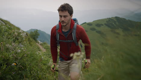 hiker in red jacket and a backpack walking up a hill on a narrow rocky path