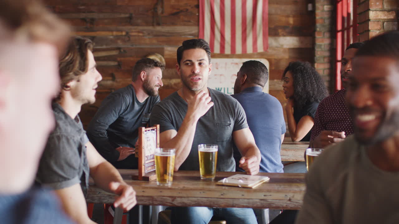 Gruppo di amici che si incontrano in un bar sportivo bevendo birra e parlando