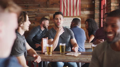 group of male friends meeting in sports bar drinking beer and talking