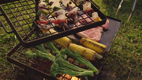 turning vegetables and meat over a fire bbq in the afternoon glow