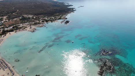 vista de avión no tripulado en grecia volando sobre elafonisi playa estrecha de arena blanca, agua azul clara en los lados y muchos paraguas en un día soleado