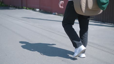 young man walking with guitar on street near forest