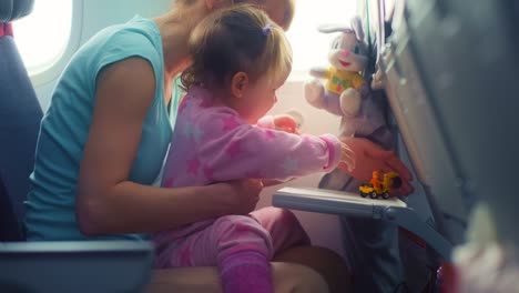 flight in airplane with baby. mother entertains her kid with toys during flight on aircraft