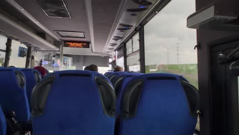 interior of a modern bus with blue seats and passengers traveling