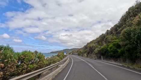 a 14-second drive showcasing lush greenery and ocean views along the great ocean road under a partly cloudy sky