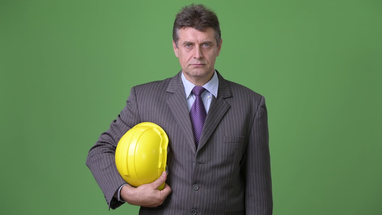 hombre de negocios maduro y guapo contra un fondo verde