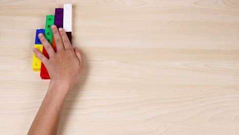 hands organize colorful cubes on a wooden surface