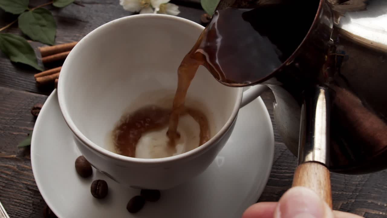 Rich Black Coffee Being Poured from Cezve into Cup on Rustic Wooden Table