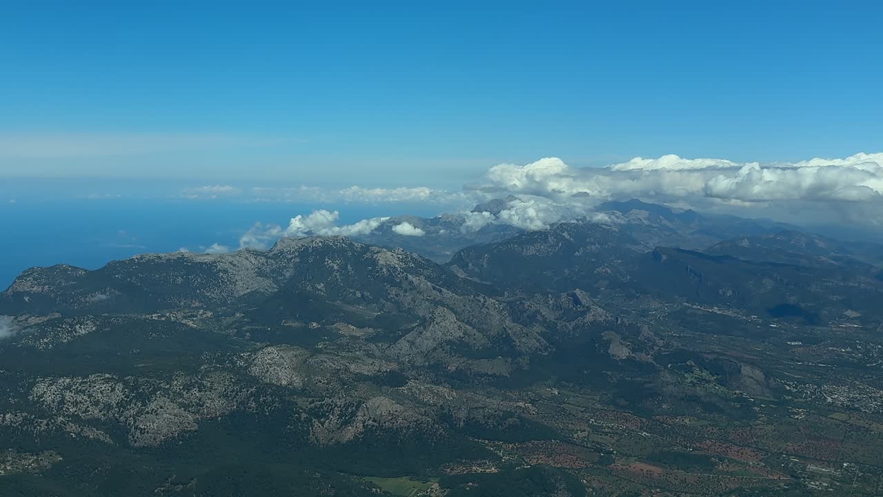 An aerial view of the Tramuntana (Tramontana) Mountains in the north of Mallorca Island, with few clouds under a blue sky. Footage taken from a Jet Cockpit.