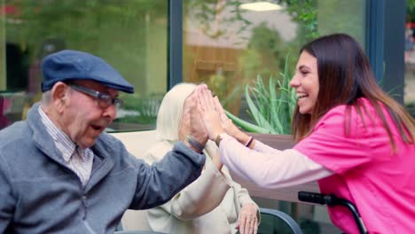 senior citizens and caregiver high-fiving in assisted living