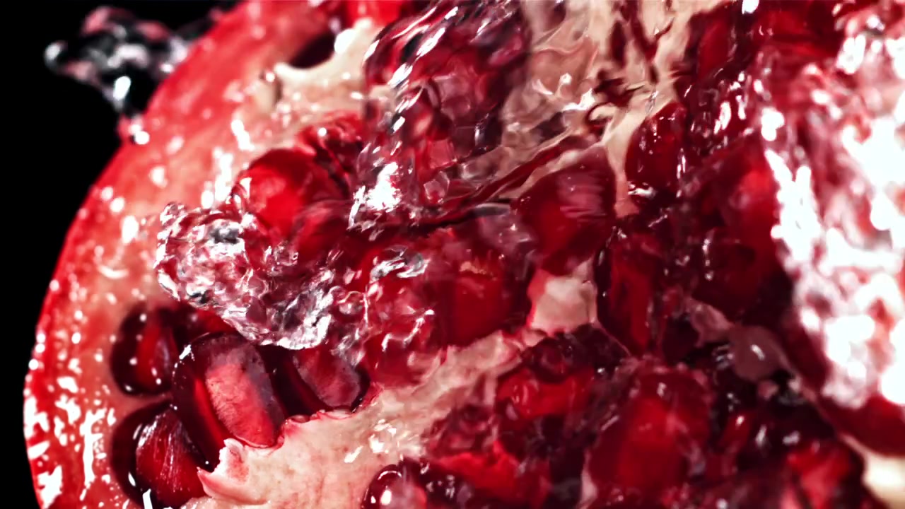 Slowmotion vand hældes over friske granatæblekerner