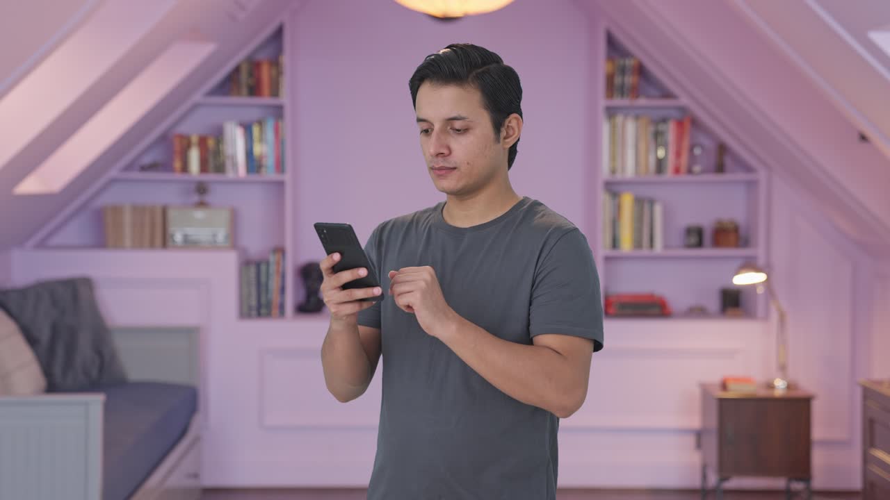 인도인 남자가 전화를 스크롤하고 있습니다.