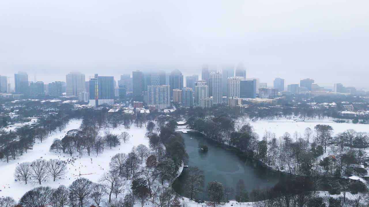 Aerial shot pulling out from snow covered Midtown and Piedmont Park in Atlanta, Georgia on January 10th 2025.