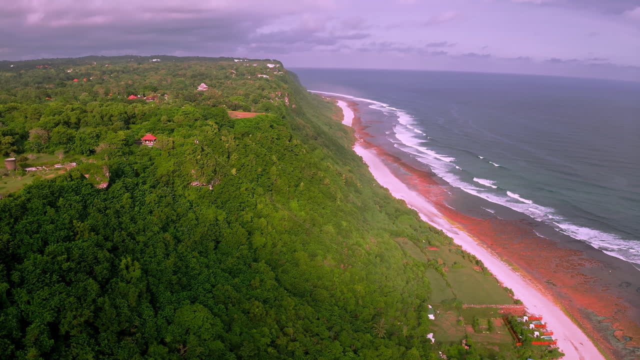 casas dispersas en el exuberante acantilado de la costa de bali por encima de la playa del océano después de la lluvia