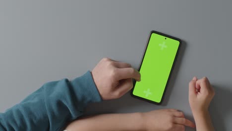 toma de estudio aérea de padre e hijo usando un teléfono móvil de pantalla verde juntos